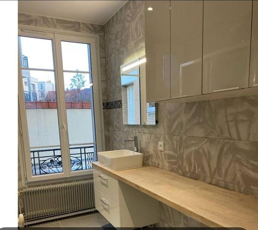 Salle de bain après travaux : plan vasque bois, faïence grand format, miroir lumineux