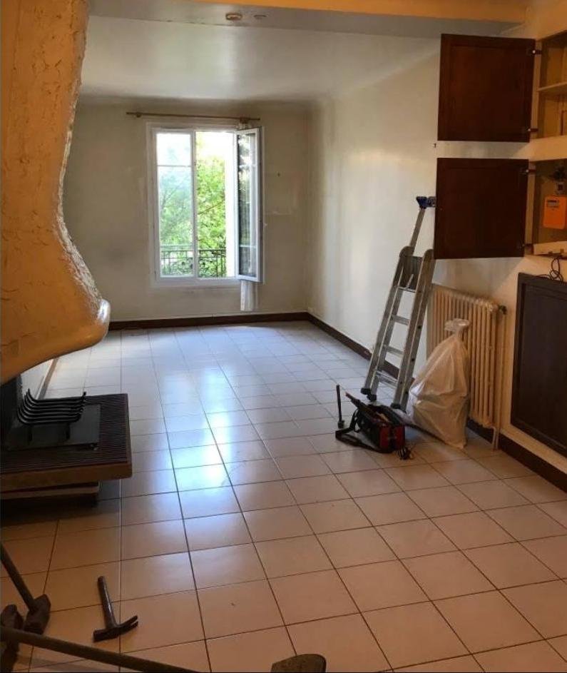 Séjour avant travaux : ancien carrelage, poutre apparente, cheminée